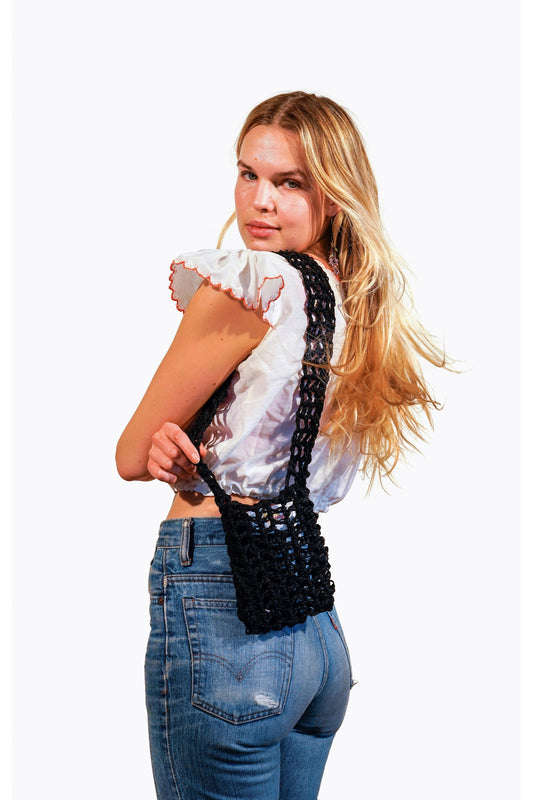 Model wearing black crochet fishnet pouch on her shoulder.
