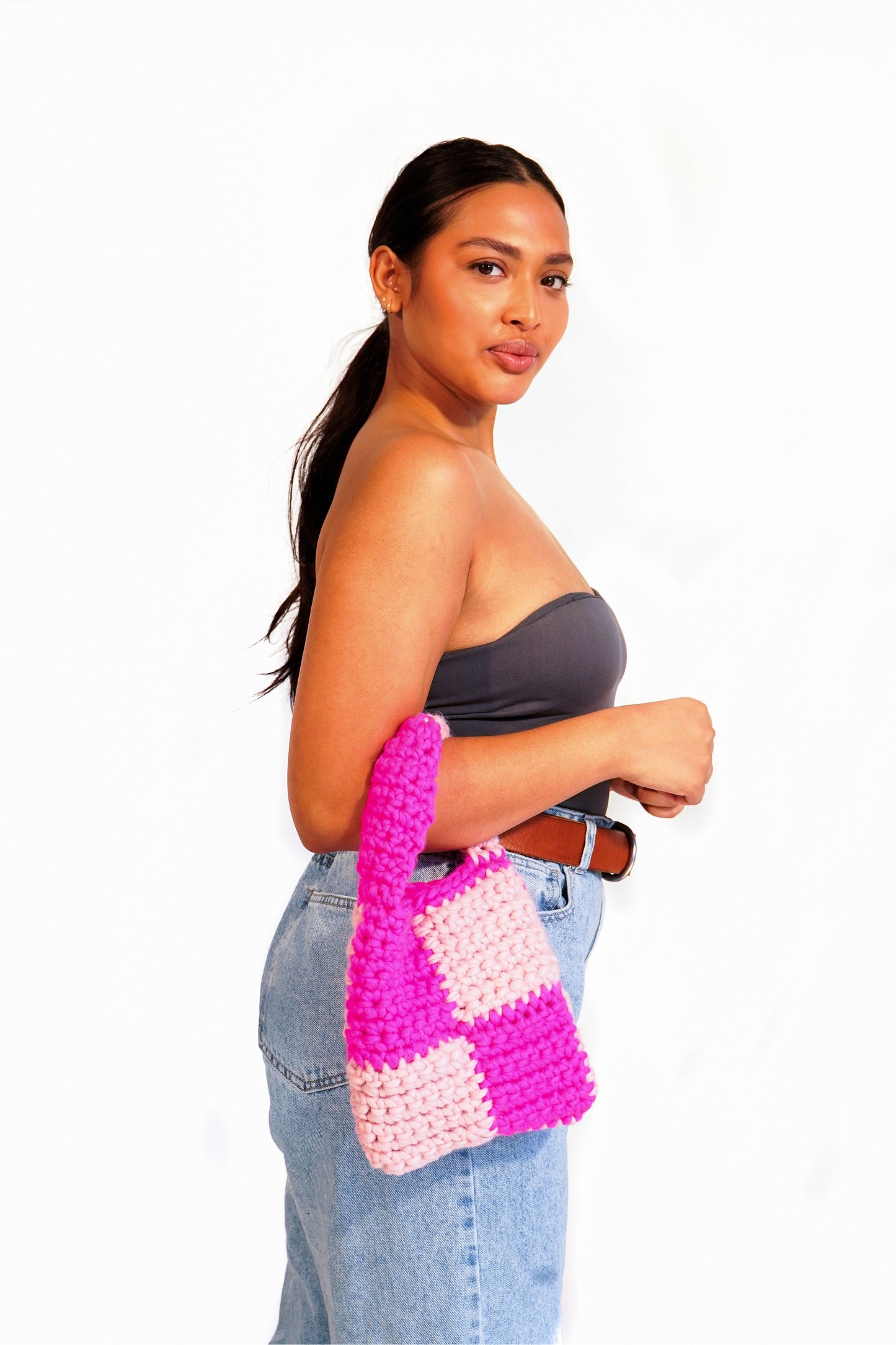 Model wearing hot pink and blush checkered crochet bag on her arm.