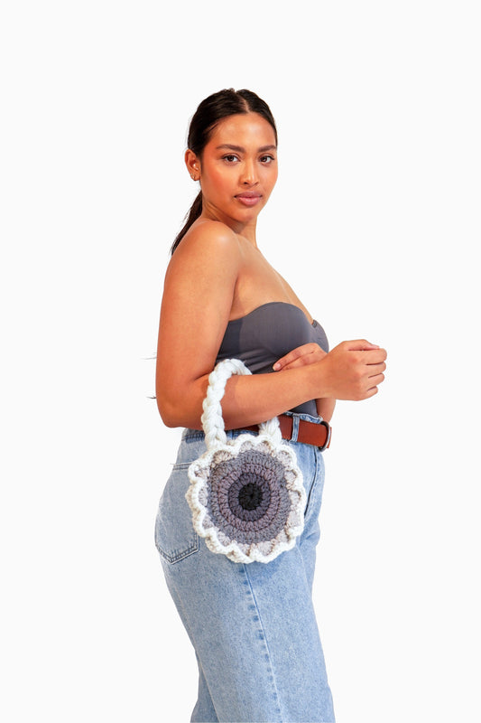 Model wearing flower shaped gray ombré crochet bag on her arm.