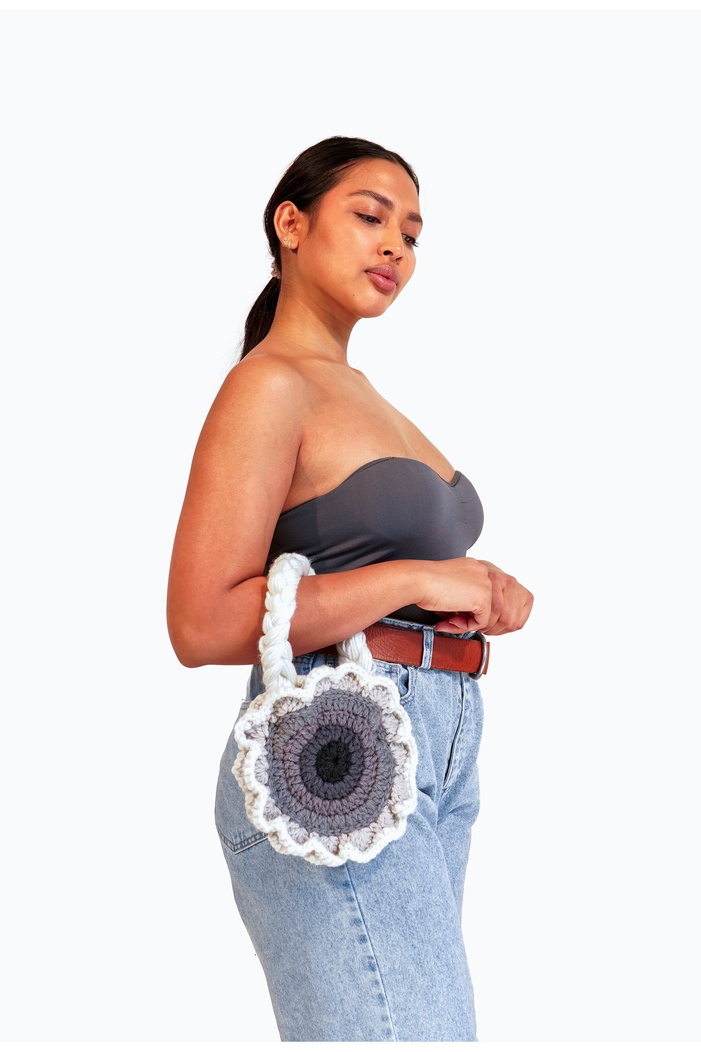 Model wearing flower shaped gray ombré crochet shoulder bag on her arm.