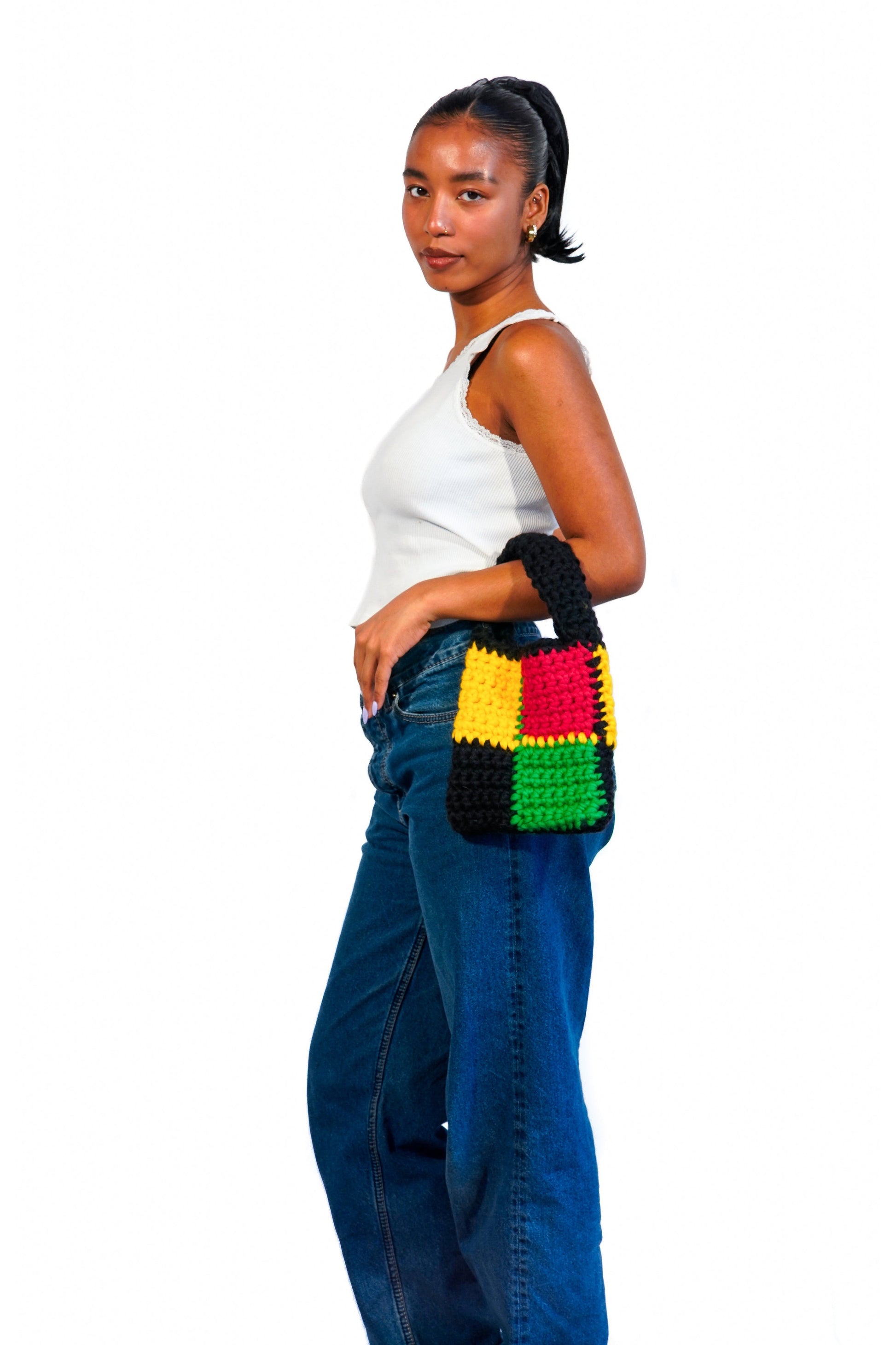 Model wearing Rasta themed checkered crochet bag on her arm.