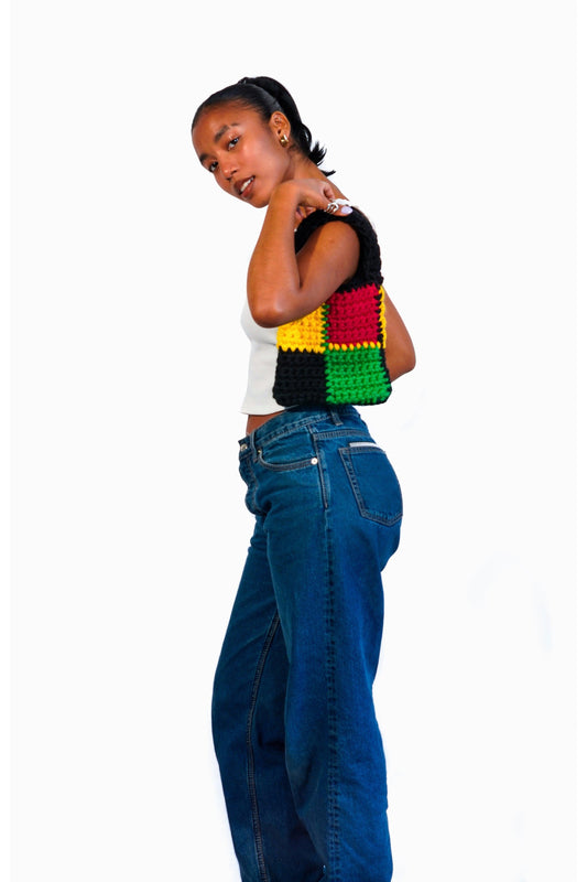Model wearing Rasta themed checkered crochet bag on her shoulder.